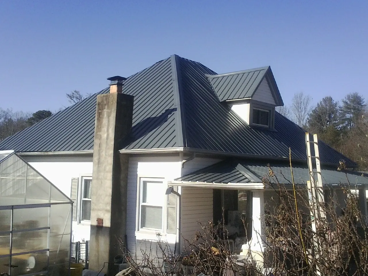 Dark blue standing seam metal roof on a white farmhouse with dormer — Slate & Tile Roof Repair by Roofing Brothers in Queenstown
