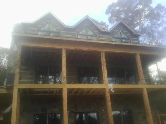 Dormers and porch framing on a large log home under construction — Roof Coating work by our crew in Queenstown