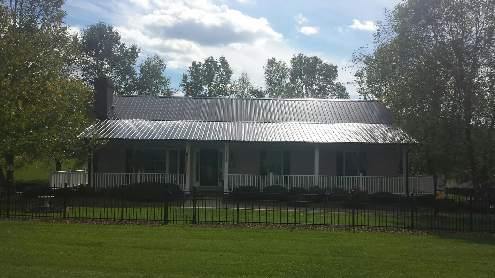 Gray metal roof on a brick ranch with a full width front porch — Gutter Guard Installation work by our crew in Queenstown