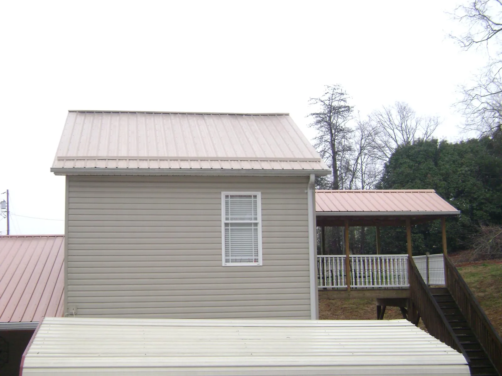 Tan metal roofs on a two story addition and attached porch, from a Roof Replacement job in Queenstown