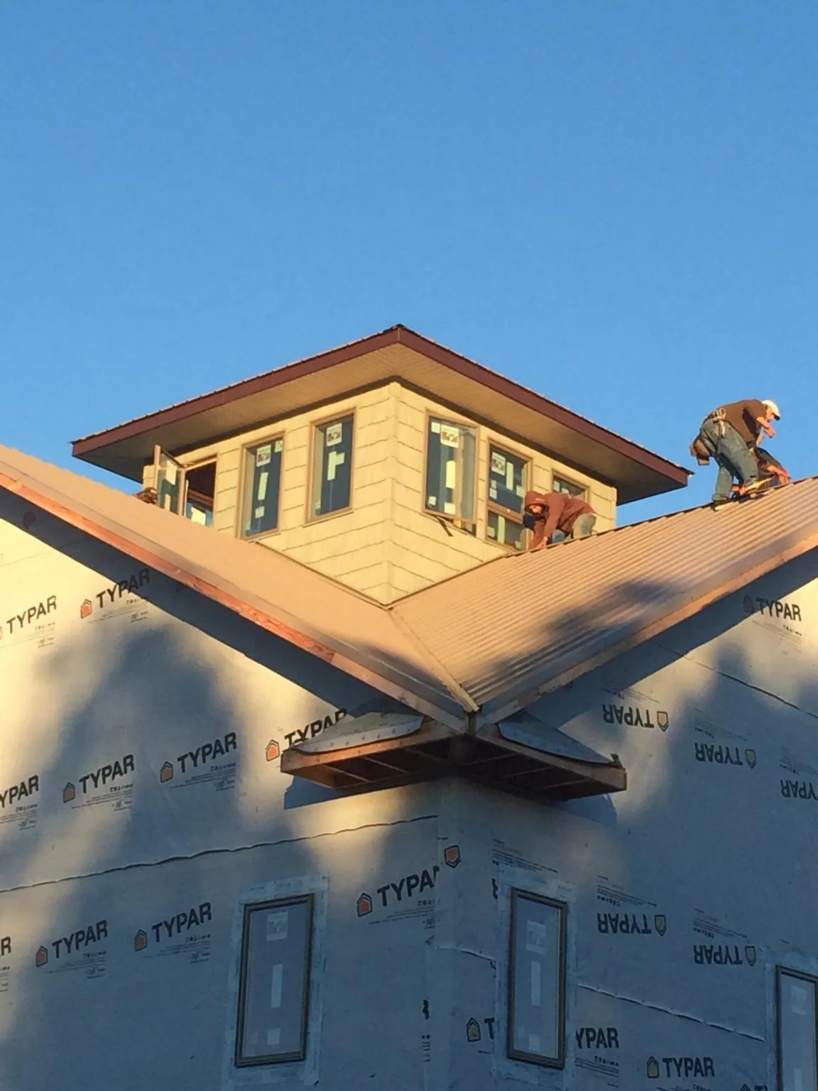 Roofers working around a rooftop cupola on a new metal roof at sunset — Roof Waterproofing in Queenstown by Roofing Brothers